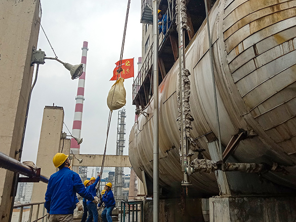 5月10日中午，在動力車間三期工藝除氧器地面，黨員突擊隊隊員用滑輪往工藝除氧器平臺運送鋼絲網(wǎng)，用以纏繞新填料.jpg